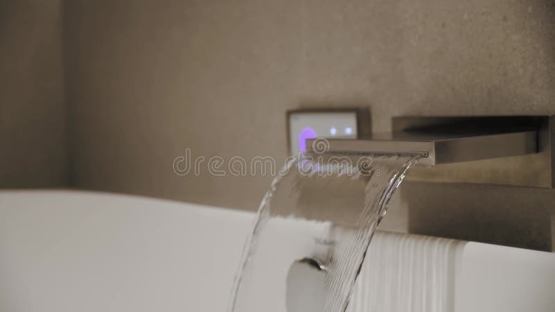 Close Up Water From The Tap Fills Into The White Modern Bath And Flows Close Up Water From The Tap Fills Into The White Modern Bath And Flows